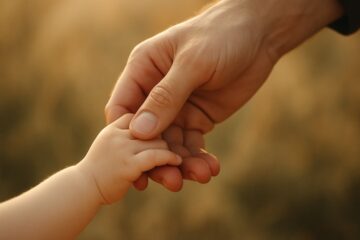 Mano adulta che stringe una mano di bambino, simbolo di amore, protezione e nuova idea di famiglia